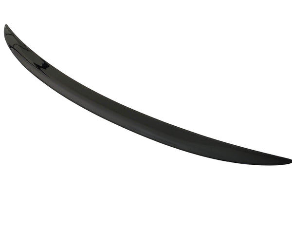 A sleek, black car spoiler lies on a plain white surface, curving slightly upward at the ends.