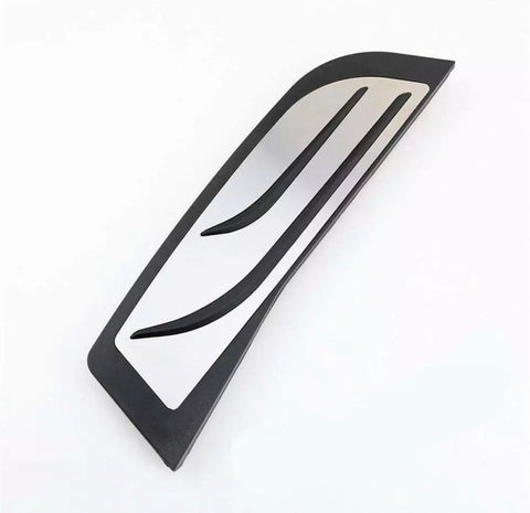 Curved metal vent with black trim, featuring two elongated slots parallel to its edges. It rests on a plain white surface.