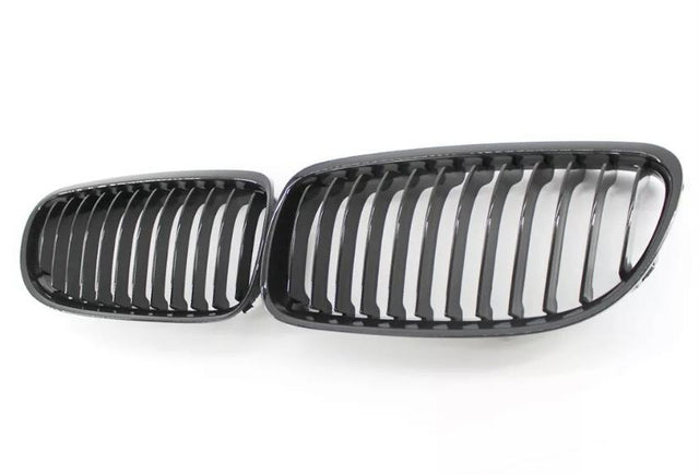 Two black car grille inserts with vertical slats lie side by side on a white background, resembling classic automotive front grille designs.