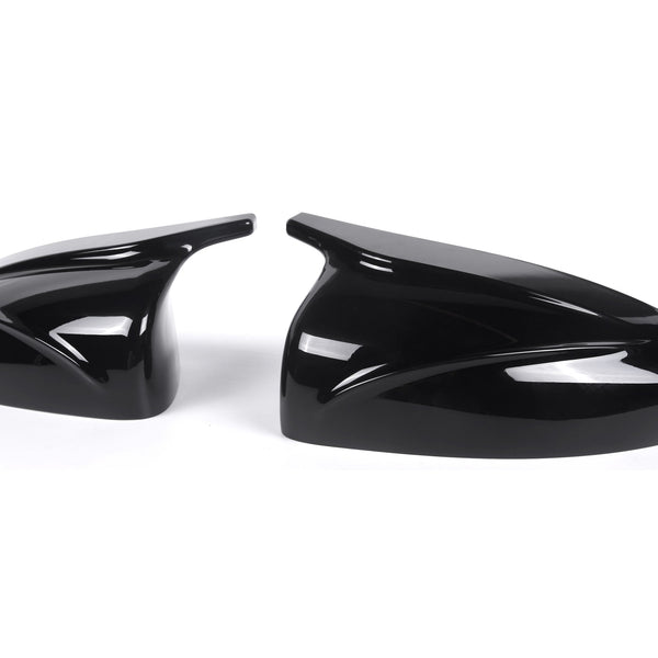Two glossy black car mirror covers rest side by side, featuring sleek aerodynamic designs, set against a plain white background.