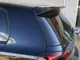A black car is parked with its rear hatch and spoiler facing a closed metal shutter. The context includes a reflection of an outdoor scene in the car's glossy surface.