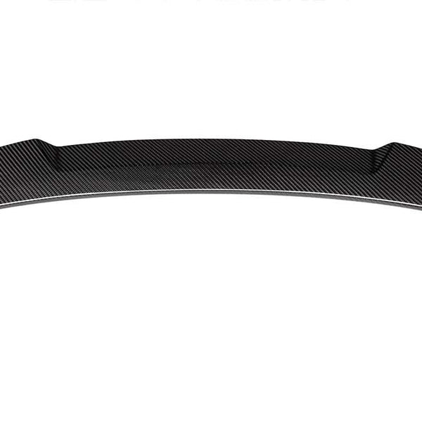 A curved carbon-fiber car spoiler rests against a plain white background, showcasing its textured, sleek design and aerodynamic build.