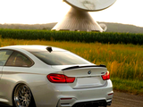A white car with glossy rims is parked on a road near tall grass, while a large satellite dish looms in the background against a sunset sky.