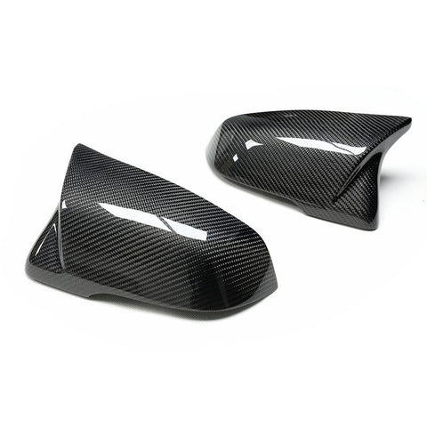 Two sleek, carbon fiber side mirror covers are positioned on a plain white background, showcasing their glossy finish and intricate weave pattern.