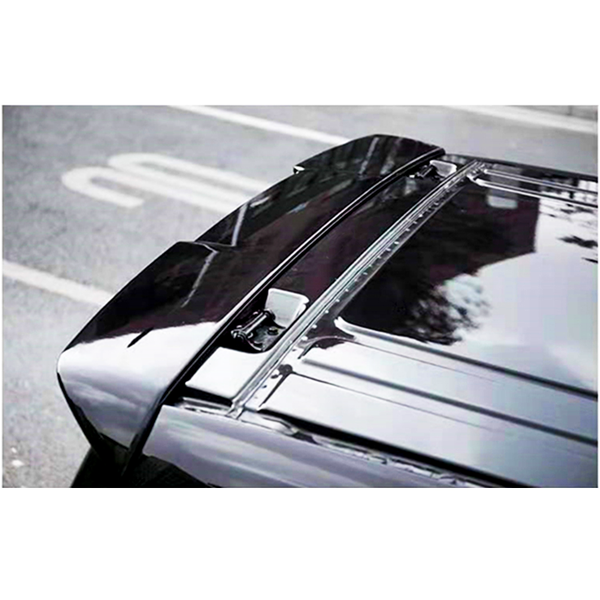 A black car roof with an attached roof rack is parked on a city street, with a blurred building and street marking visible in the reflection.