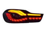 A car tail light features illuminated red and amber LED segments arranged in a modern, angular design, set against a black background.