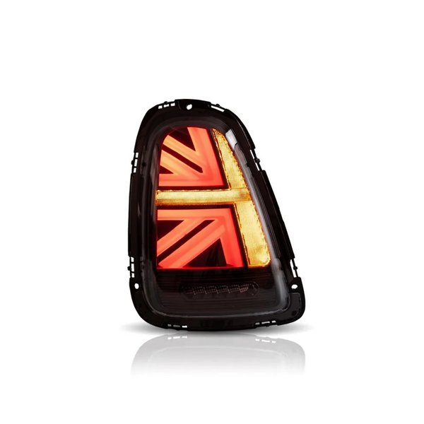 The object is a car taillight with a glowing red and amber graphic resembling a Union Jack. It's isolated against a plain white background, highlighting its distinctive design.