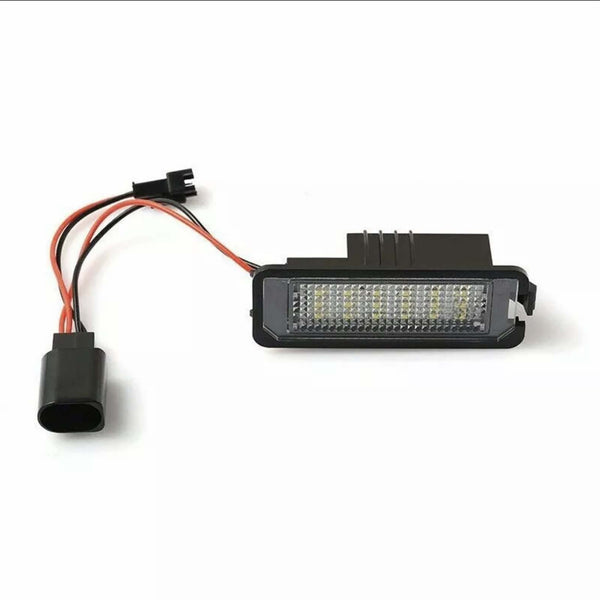 Rectangular LED light with multiple small bulbs is connected to red and black wires ending in a plug, placed on a plain white surface.