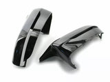 Two glossy black car mirror covers rest on a plain white surface, showcasing their sleek, curved design and reflective finish.