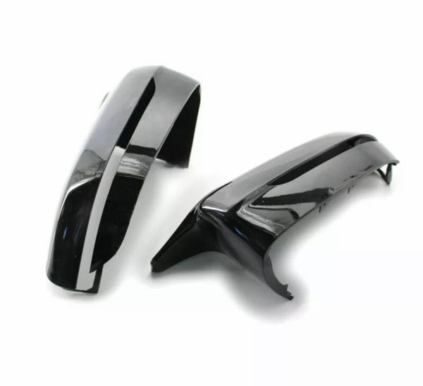 Two glossy black car mirror covers rest on a plain white surface, showcasing their sleek, curved design and reflective finish.