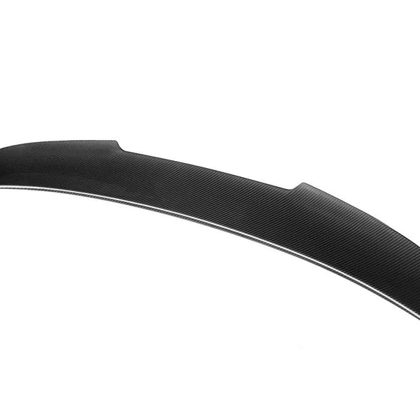 Curved carbon fiber car spoiler resting against a white background, showcasing its sleek, aerodynamic design with subtle texture details.