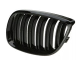 A shiny, black automotive grille with vertical slats is lying on a plain, white background, likely for use as a vehicle front intake or trim component.