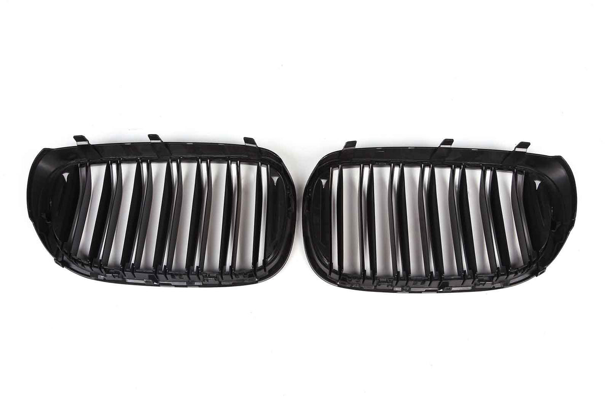 Two black car grille inserts with vertical slats lie side by side against a white background, designed to fit into a vehicle's front end for ventilation.