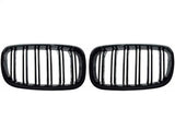 Two black, rectangular car grilles with vertical slats are symmetrically positioned on a plain white background, showcasing a sleek design.