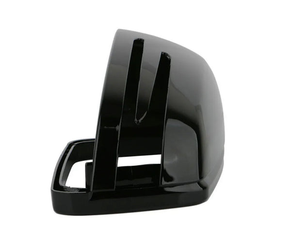 A glossy black, curved plastic object with slots, resembling a vehicle side mirror cover, sits isolated against a plain white background. No text is present.
