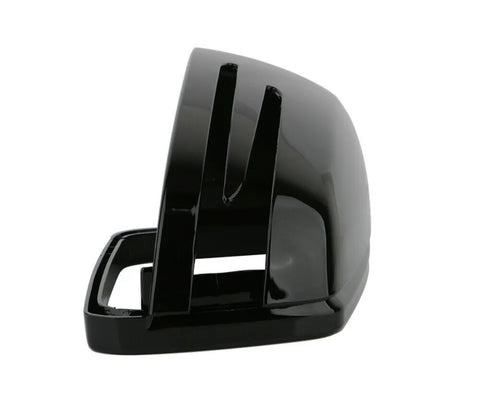A glossy black, curved plastic object with slots, resembling a vehicle side mirror cover, sits isolated against a plain white background. No text is present.