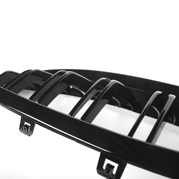 A black car grille features horizontal slats with connectors, set against a white background, highlighting its glossy finish and sleek design.