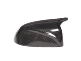 A sleek carbon fiber car mirror cover, reflecting light, sits against a plain white background, highlighting its glossy, textured surface and aerodynamic design.