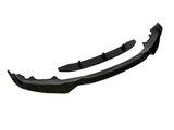 A black car front lip spoiler kit lies on a white background. The main curved piece is accompanied by a smaller, straight piece with three fins, designed for vehicle aerodynamics.
