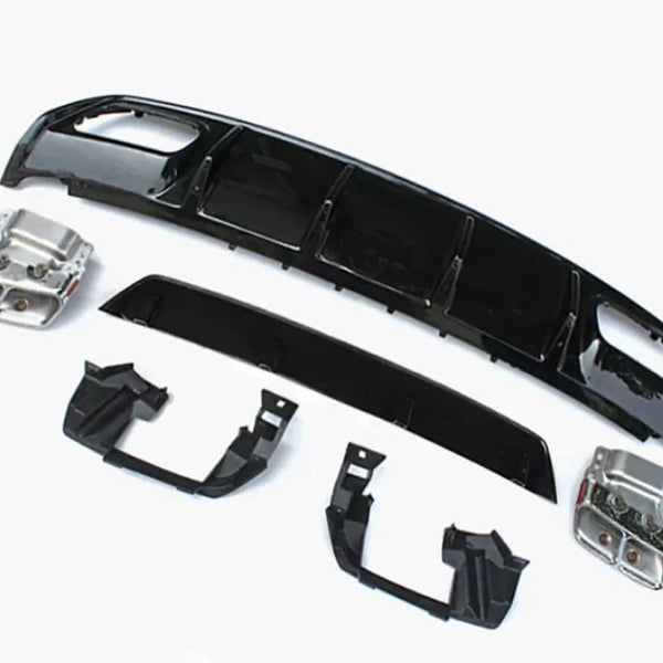 Car bumper components lie on a plain white surface, including black plastic and metallic parts arranged separately, showcasing a disassembled view typical for repairs or upgrades.