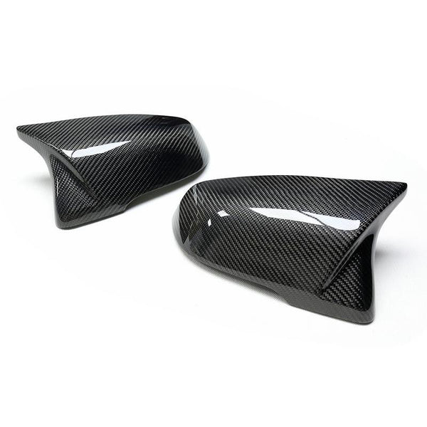 Two carbon fiber car side mirror covers are placed on a white surface, showcasing a glossy finish with fine diagonal patterning.