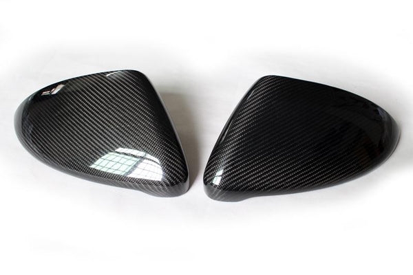Two carbon fiber car side mirror covers lying on a white surface, displaying a sleek, glossy pattern with no visible text.