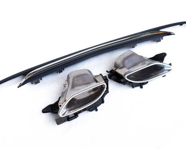 Car exhaust tips and diffuser lie on a white surface, highlighting their metallic and plastic construction. The exhaust tips show a chrome finish, while the diffuser is black and elongated.