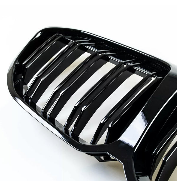 A glossy black car grille with vertical slats sits on a white background, showcasing its reflective surface and designed for air intake efficiency in a vehicle's front exterior.