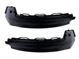 Two black, curved, plastic automotive parts with angular edges are positioned horizontally. Each features the text 