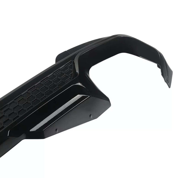 A black car bumper with a hexagonal pattern design lies against a plain white background, showcasing its sleek, modern contouring and aerodynamic style.