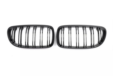 Two black, oval grilles with vertical slats are positioned side by side on a plain white background.