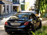 A black Mercedes-Benz C43 car is parked on a narrow, sunlit street lined with buildings and greenery. A sign reads 