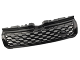 A black car grille features a honeycomb pattern, with a smooth emblem section. It rests in isolation against a plain white background.