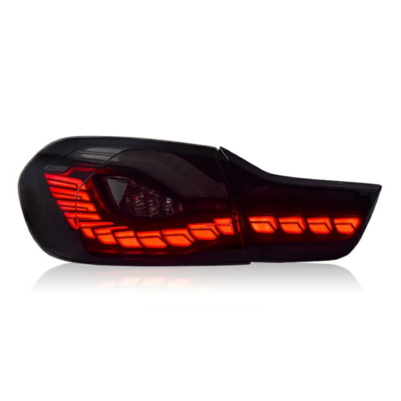 A sleek car taillight is illuminated with vibrant red LED segments, arranged in a distinctive, angular pattern. It is set against a plain, white background.