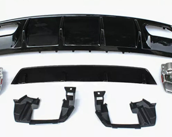 Assorted car parts, including a large black bumper and metallic components, are laid out on a plain white surface, arranged neatly for display or assembly.