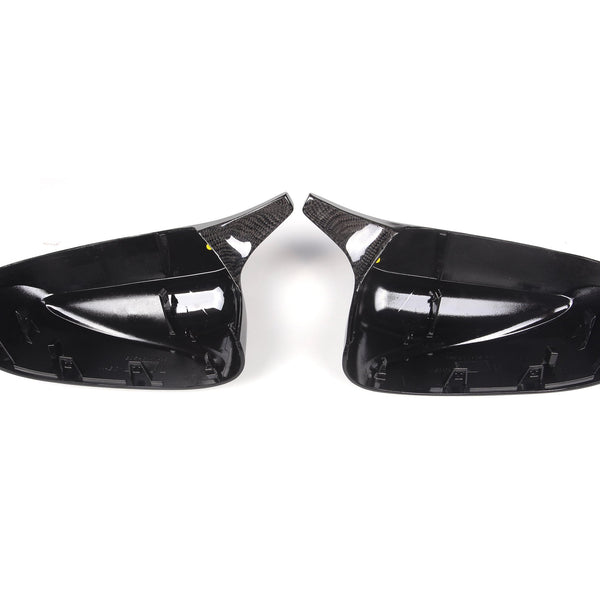 Two glossy black car side mirror covers face each other against a plain white background. The covers are sleek with internal mounting clips visible.
