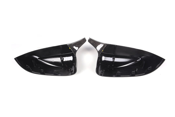 Two glossy black car side mirror covers face each other against a plain white background. The covers are sleek with internal mounting clips visible.