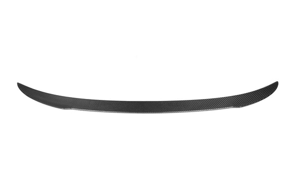 A carbon fiber car spoiler is displayed, streamlined and slightly curved, set against a plain white background, emphasizing its sleek, lightweight design.