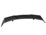 A black car spoiler slightly curved upwards, positioned on a plain white background. The surface has a textured pattern, indicating a potential carbon fiber material.