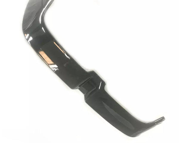 A glossy black car spoiler with an angular design rests on a plain white background.