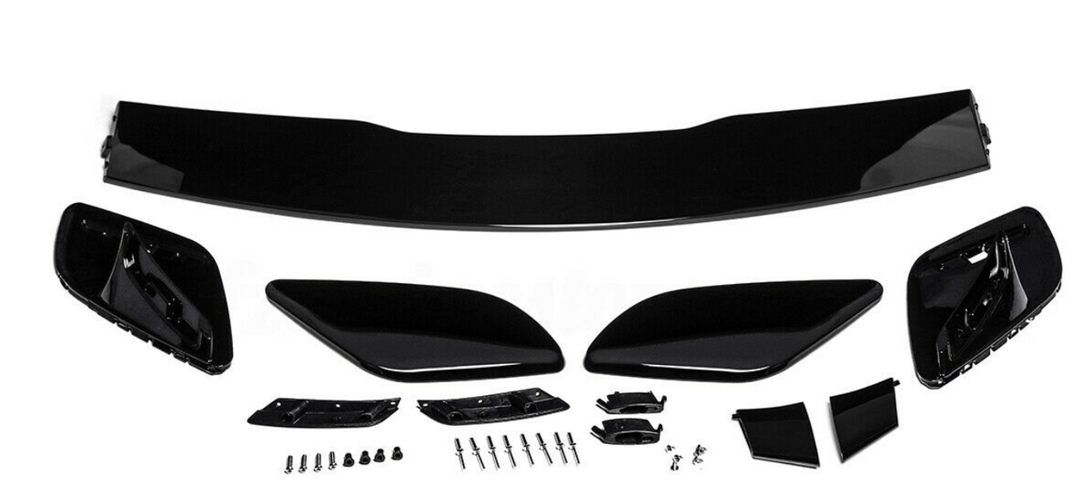Car spoiler kit with black aerodynamic components laid out on a white surface. Includes a large wing, side pieces, and multiple small parts and screws for assembly.