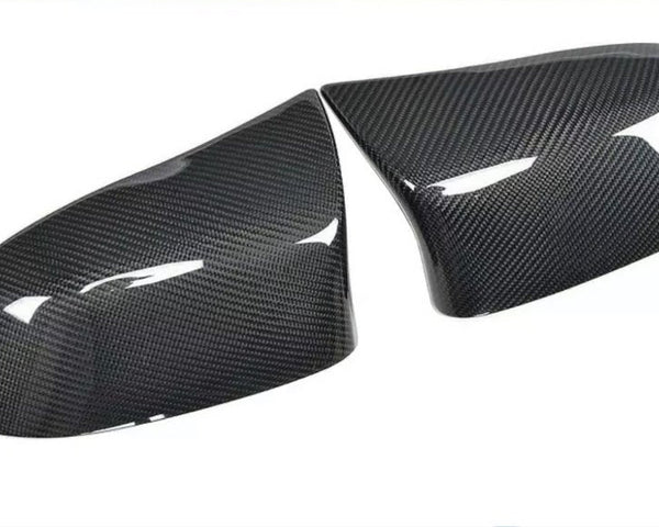 Carbon fiber car mirror covers, positioned side by side, displaying a glossy surface with visible texture, set against a plain white background.