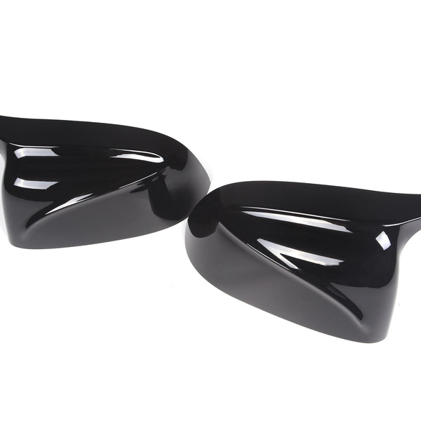 Two glossy black side mirror covers reflect light, positioned on a white background. The covers have a sleek, aerodynamic design, suggesting use for a vehicle.
