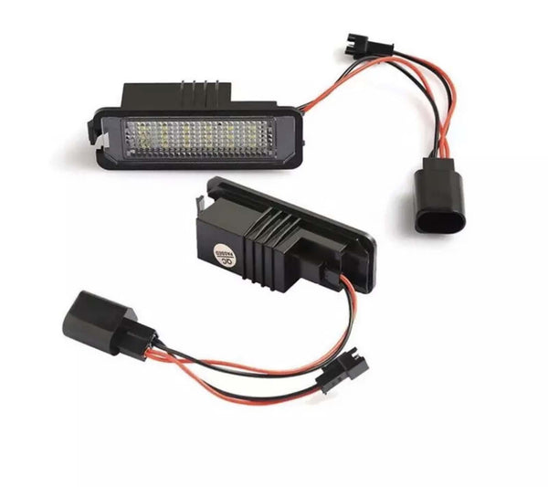 Two rectangular LED car lights connected by wires rest on a white surface. One light is face up, revealing numerous small LED bulbs. The other is slightly angled, showing its black casing.