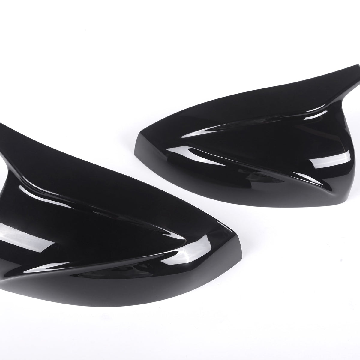 Two sleek, black, aerodynamic car mirror covers lay side by side on a plain white background, emphasizing their glossy finish and curved design.