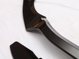 A glossy black automotive trim piece lies on a white surface, featuring smooth, angular shapes and reflective curves, suggesting a component for vehicle customization or aesthetics.