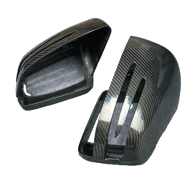 Carbon fiber car mirror covers rest on a gray carpet. One cover is upright, showing slot designs, while the other is on its side, revealing the inner structure.