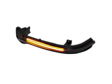 A curved car side mirror LED turn signal emits amber light, positioned against a plain white background.