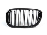 A shiny black car grille features vertical slats framed by an oval shape, set against a plain white background.
