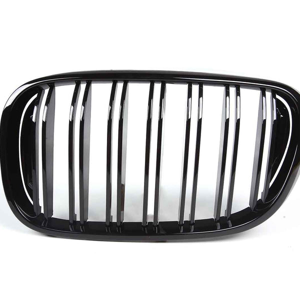 A shiny black car grille features vertical slats framed by an oval shape, set against a plain white background.